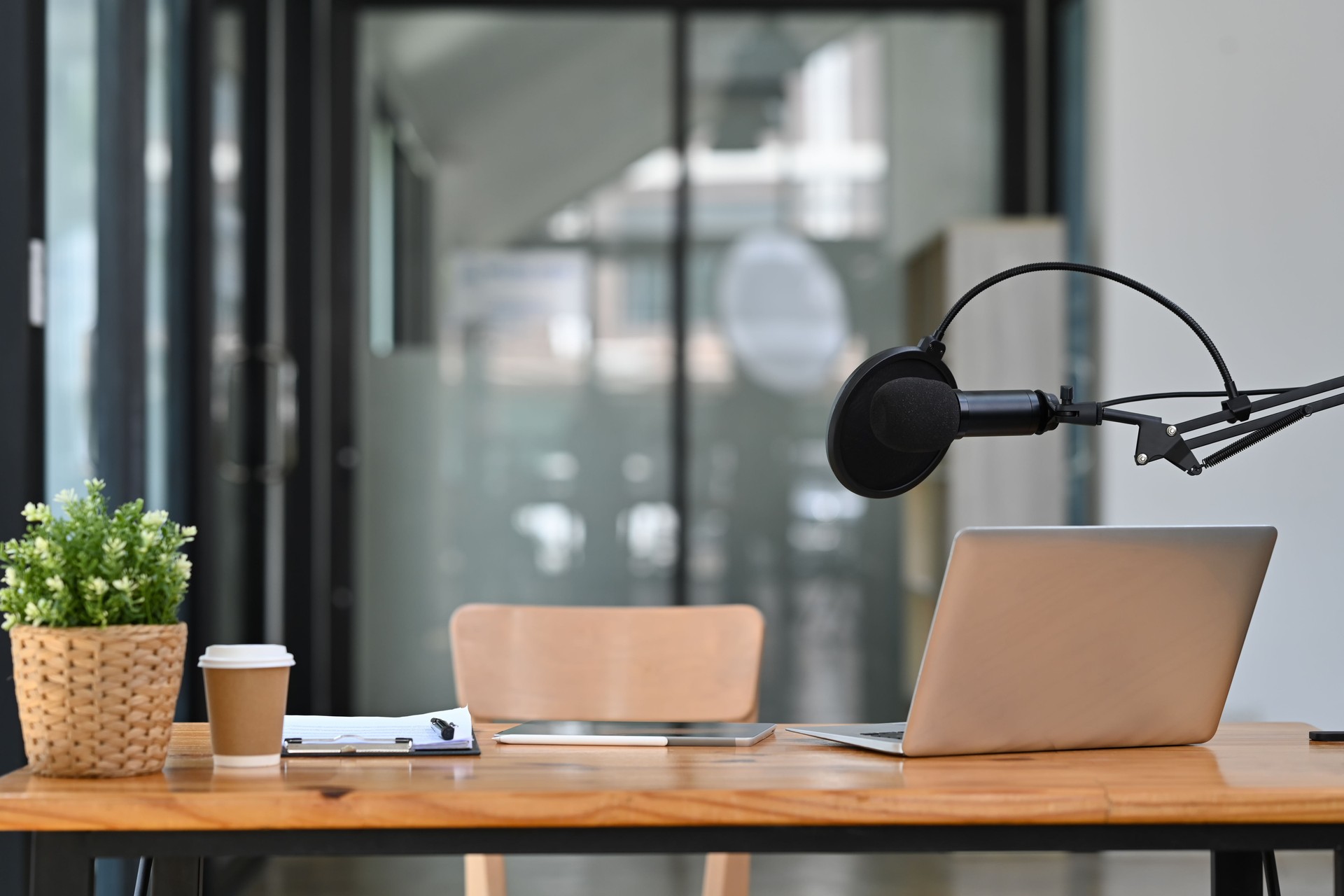 Studio podcast interior with professional condenser microphone and laptop on wooden table. Technology and audio equipment.